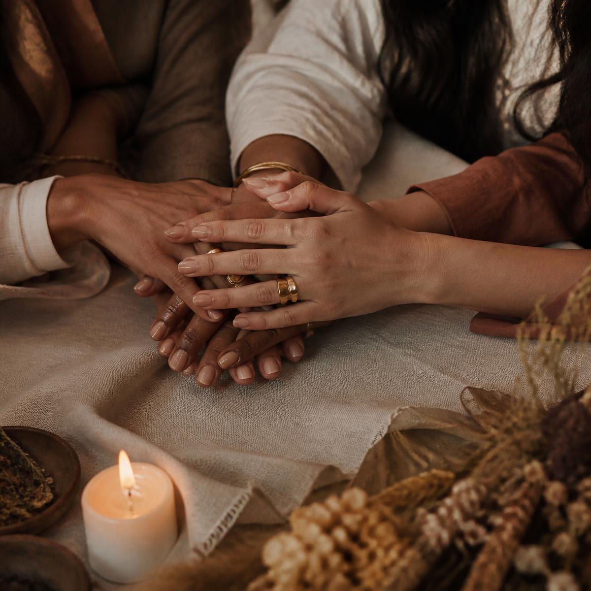 Women's hands resting together over warm linen by candlelight